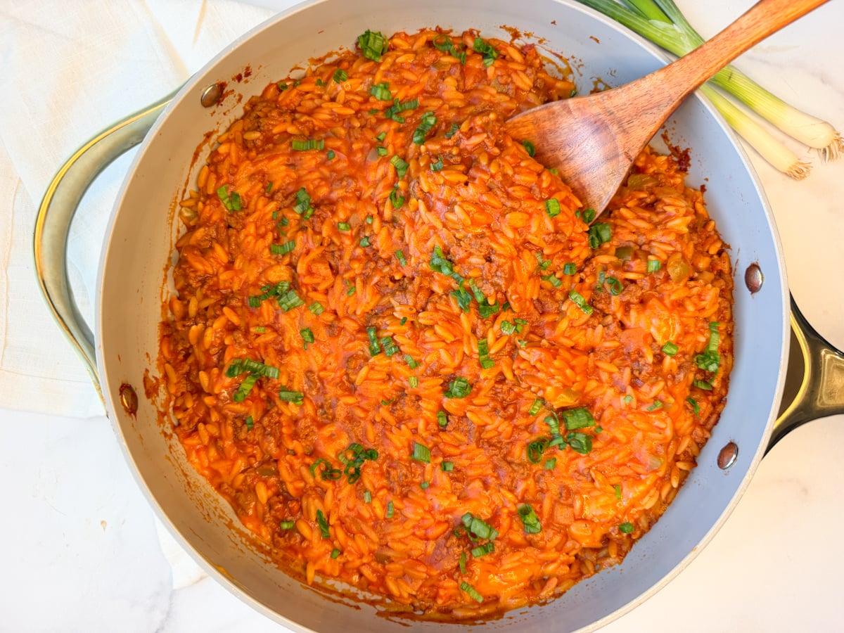 Sloppy joe orzo skillet with ground beef, tomato sauce, melted cheddar and green onions